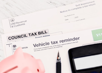 the council tax bill, vehicle tax reminder, tax self-assessment, piggy bank, calculator, pen on the...