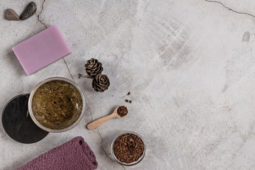 On a gray background are accessories for Spa self-care: body scrub, ground coffee, lavender soap, Terry towels for face and body