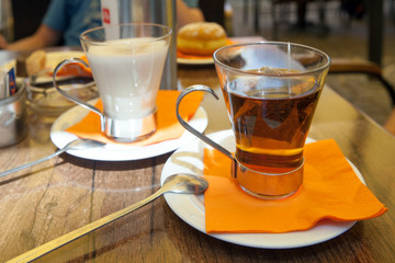 Cup of tee and cap of hot milk are standing on table in cafe, Italy