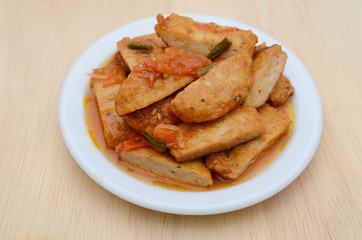 fried fishcake slices with stew sauce in plate