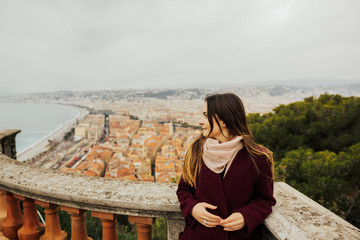 Fototapeta na wymiar Young female traveler enjoying great view on the Nice city, France. Beautiful panoramic aerial cityscape top view of Nice, of French riviera. Landscape of harbor, town of Cote d'Azur France.Copy space