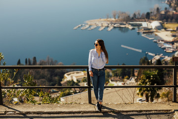 Traveller at the top peak of Monte San Salvatore in Lugano, Switzerland. Overlooking the lake town. Young girl looking at the panoramic scenery. Young girl admiring the alpine landscape. Copy space.