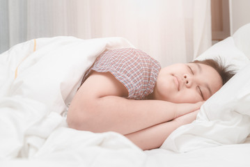 cute obese asian boy sleep on bed in the bedroom.