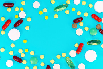 Assorted pharmaceutical medicine pills, tablets and capsules over blue background