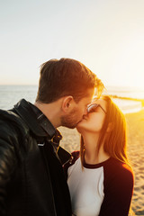 Amazing beautiful  couple make selfie on the beach in sun light. Kissing couple enjoying sunny day together. Couple in love relax on beach. Sexy woman and man make selfie at sea. Passion. Copy space.