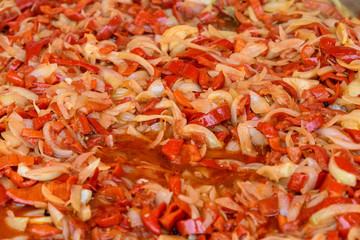 Large portion of vegetarian food prepared with chopped red tomatoes and onions prepared as side dish and displayed for sale at a street food market, side view of healthy plant based food
