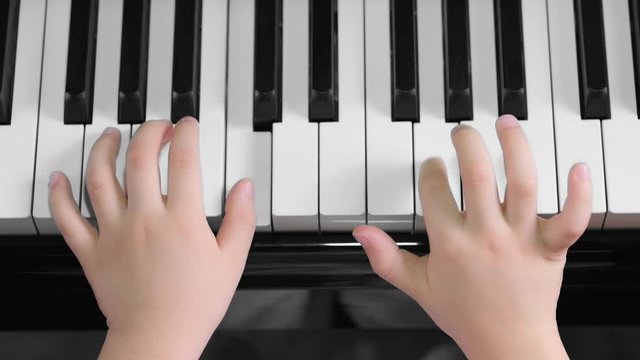 Top view of closeup Asia boy playing piano at home. Used ten fingers to press piano key. Feeling fun, happiness and relaxation. Piano lesson. Musical instrument and practice concept.