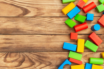 Colorful wood toy building blocks on wooden background. Space for text.