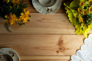 kompozycja filiżanki i kwiatów ma tle stołu sosnowego.