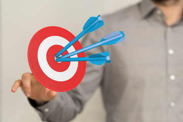 hand holding a target with darts hitting the center over white background. Concept of .