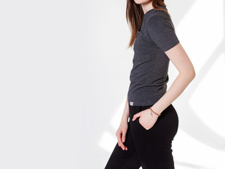 Young girl wearing blank t-shirt and and sport pants. Gray wall background shadow light from the window with copy space for your text message or promotional content