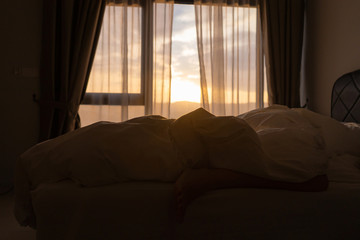 Foot sleeping in the morning at dawn, the girl hangs down the bed. Spy photo. Deep sleep.