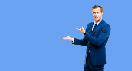 Businessman showing something, isolated over blue color background. Copy space for some slogan or...