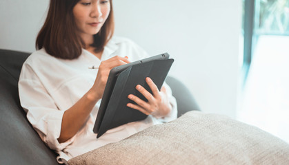 young woman working on tablet computer while sitting at the bedroom. work from home concept