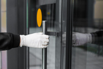 a gloved hand opens the door on the street. man in gloves holds a doorknob