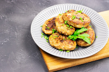 fresh meat fried cutlets with greens on a plate, close-up. brutal men's food on a wooden stand on a black stone table