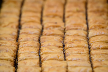 Close up of traditional oriental sweet pastry cookies known as backlava, Turkish desert with sugar, honey, walnuts and pistachio, in display at an weekend street food market, top view, soft focus
