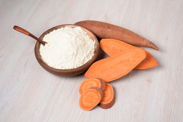 sweet potato flour in a wooden plate. sweet potatoes are a vegan organic ingredient for healthy eating on a light background.