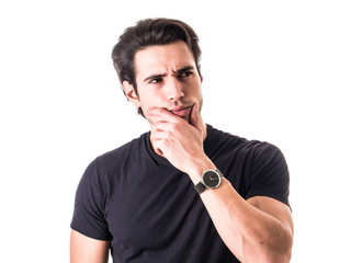 Dubious, unsure handsome young man isolated on white background