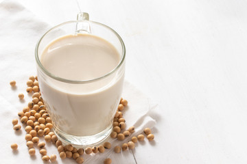 Soy or soya milk in a glass with soybeans background
