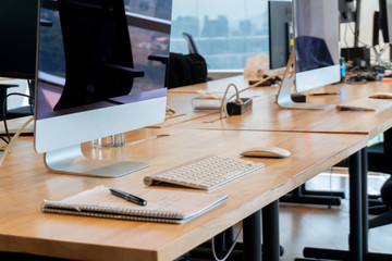 Modern office interior with many computers and a notebook with a pen with some annotations