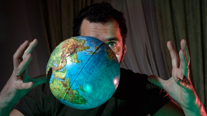 A man in a medical mask on the insulation of the house. A man is ill at home. Dreams of traveling in a pandemic. A man with a globe in his hands. Coronavirus pandemic.