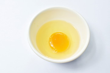 raw egg with yolk  in cup on white background