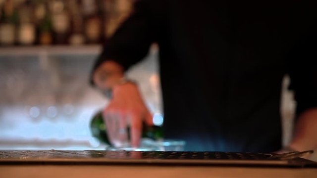 A bartender silhouette prepare a cocktail on a bar background, close-up.