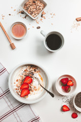 top view of breakfast table with yogurt bowl strawberries muesli honey and coffee
