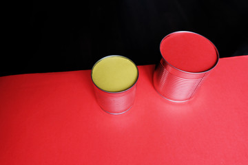 Bright, colorful and color horizontal shot of cans with yellow and red paints on a red surface and black background with empty place for text