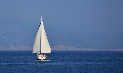 white sailboat with people on the high seas