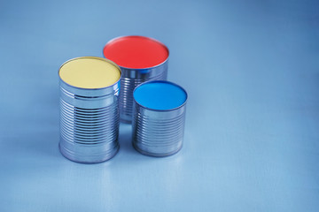 Bright, colorful and color horizontal shot of cans with yellow and red paints on a blue background with empty place for text on the right side