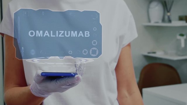 Doctor in medical glove against background of doctor's office with HUD hologram text Omalizumab. Hand holds futuristic holographic gadget. Medical technology concept of the future