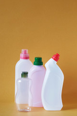 Vertical shot of plastic rolls of chemical products - fabric softener, soap, dish detergent and duckling for the toilet on a yellow background - still life. Empty space for text in a vertical shot