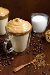 cold dalgon coffee in clear glasses on a dark wooden background. foam from sugar and instant coffee is whipped with a mixer over cold milk. Indian national whipped coffee. coffee beans