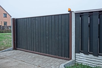 gray black private gate and wooden plank fence on a rural street