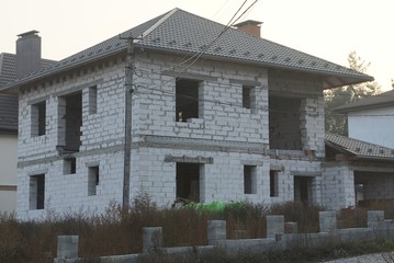 one large unfinished private house of white bricks on the street against a gray sky