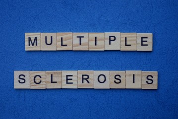 phrase from gray words multiple sclerosis from small wooden letters on a dark blue table