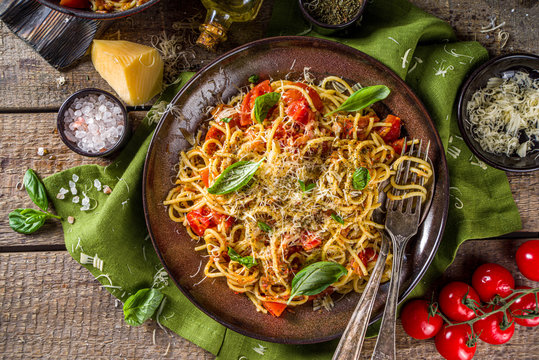 Traditional Italian pasta marinara. Classic recipe Roman food - pasta bucatini amatricana, with basil leaves on wooden rustic background