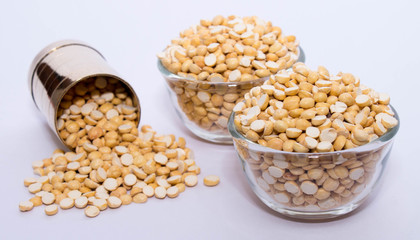 Group of a healthy roasted gram in a bowl with brass measuring jar on a white background