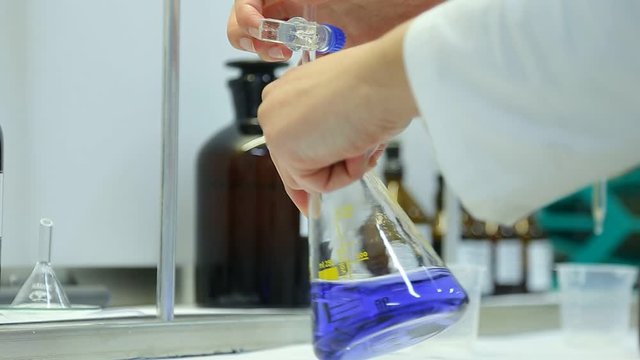 Chemical laboratory research in a scientific laboratory. The chemist holds a glass flask in his hand.