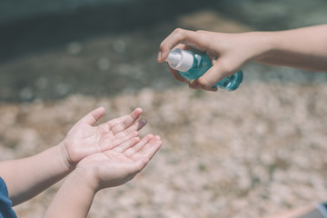 An Asian mother is spraying alcohol for her daughter to kill the bacteria and prevent the infection of the Covid-19 virus. Outbreak and spread