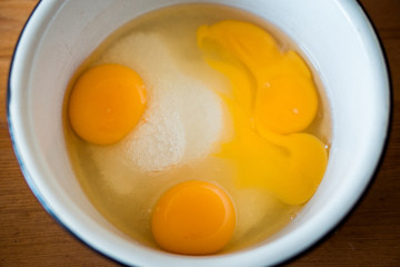 two raw broken eggs in a bowl with sugar. preparation of Christmas pastries. preparation for the holiday. kitchen utensils