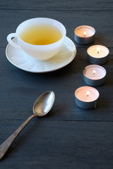A cup with green tea and candles