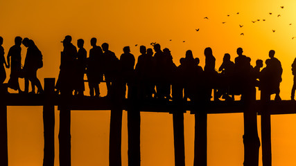 Contraluz de personas al atardecer caminando en el muelle