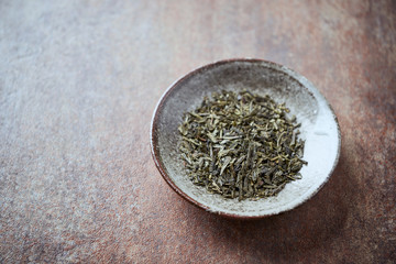 Fototapeta na wymiar Dried Green Tea Leaves on Rustic Stone Background. Close up.