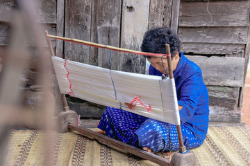 Craftsperson working. Old woman process homespun cotton fabric weaving in community. Senior women...