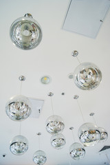 The interior design element of a huge store is the original form of transparent round glass ball-lamps of silver color.