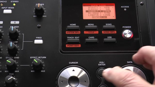 A man&rsquo;s hand operating a digital multitrack audio recorder, to check music being created in a studio. This is a standalone piece of electronic hardware / equipment.