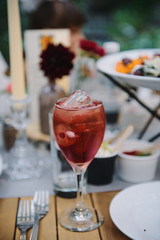 Pink cocktail with ice on a table at a party.